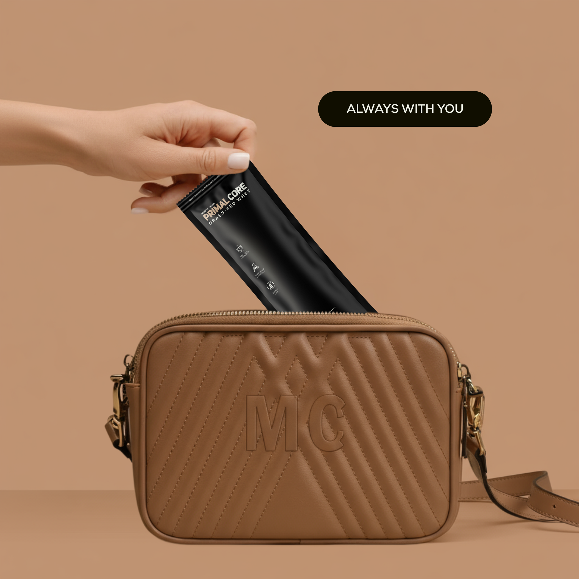 Brown handbag with Mindful Crumb 'MC' logo being opened by a hand, with a black primal core protein sachet inside on a beige background.